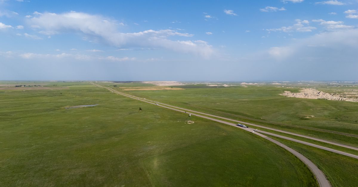Breathtaking aerial view of vast grasslands spreading under a clear blue sky, highlighting natural beauty.