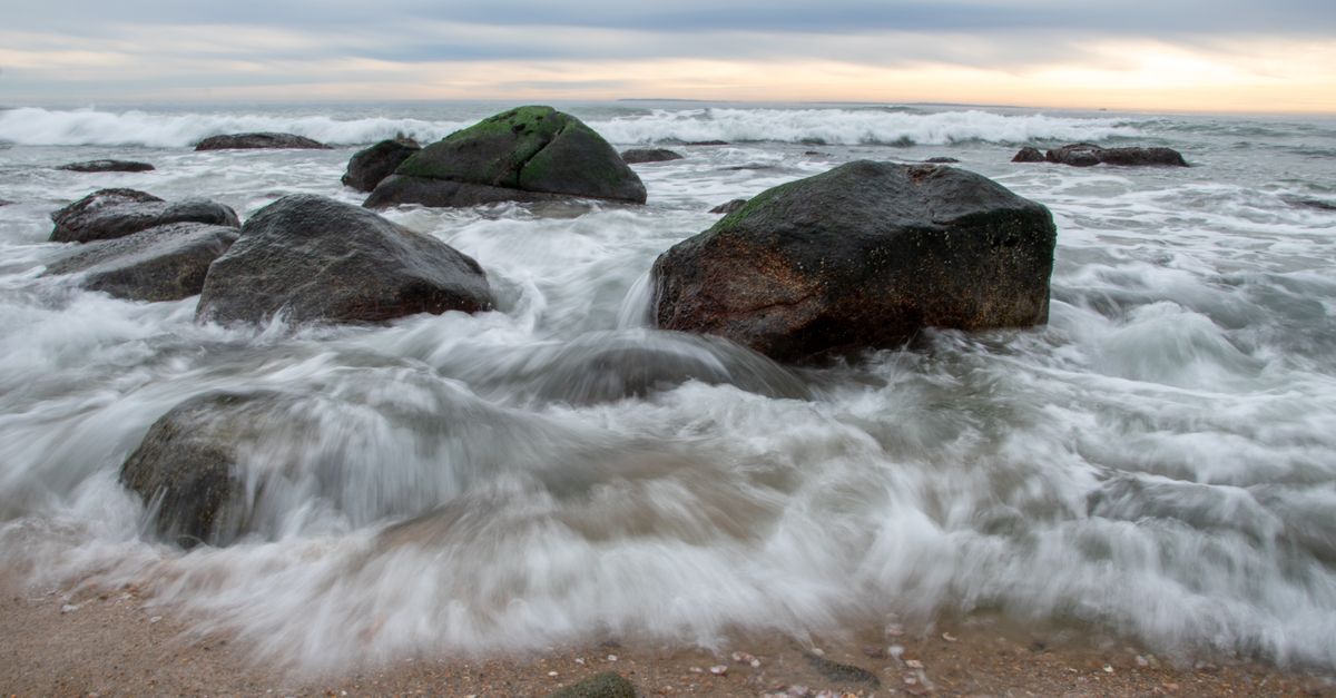 Dynamic ocean waves crashing over boulders at Charlestown Beach, Rhode Island.