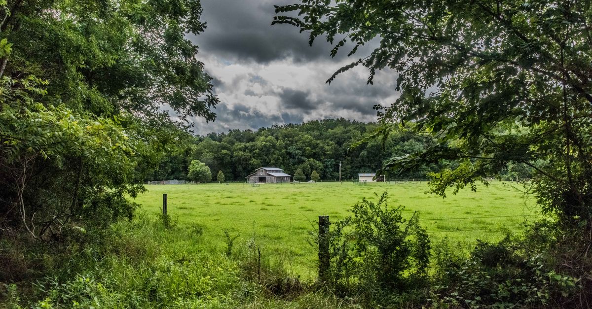 Scenic view of a barn amidst green fields and cloudy skies in Alto, Tennessee.