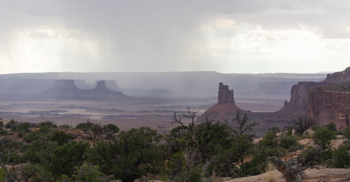 Breathtaking view of the rugged canyon landscape in Moab, Utah under overcast skies with rain showers.
